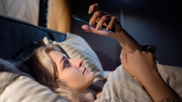 жена гледа у телефон уместо да спава