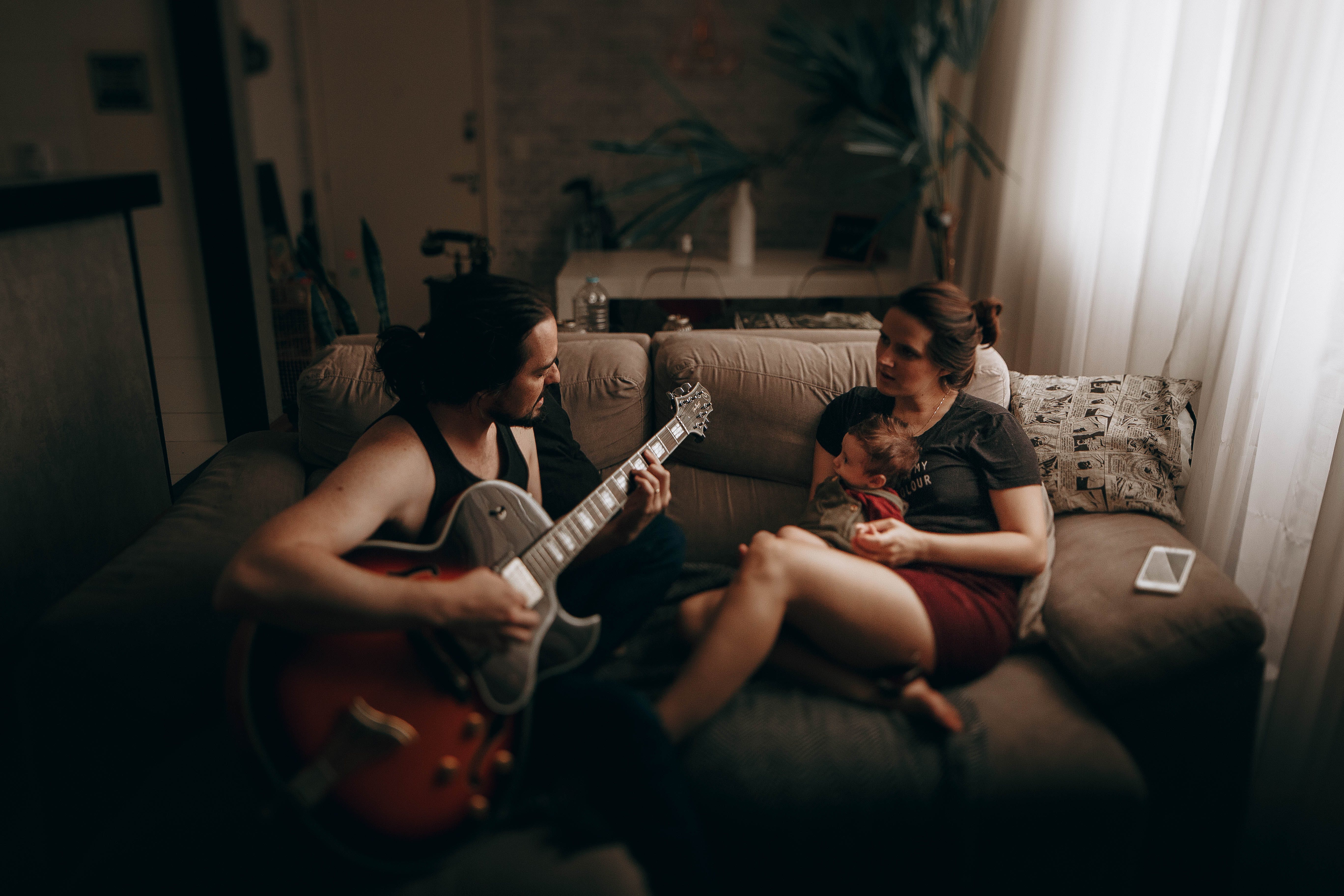 Отац свира гитару док мама и беба слушају