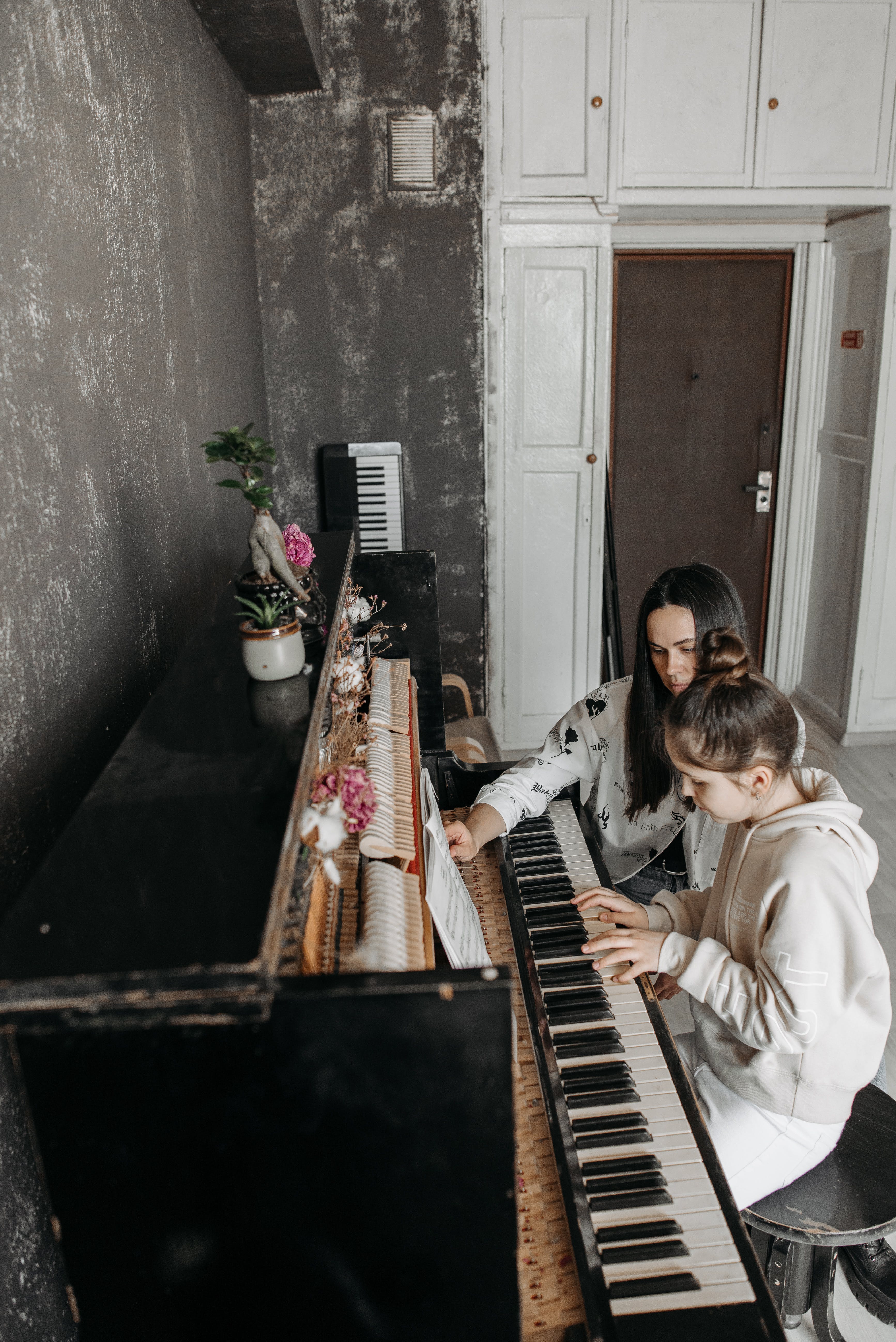 Девојчица учи да свира клавир успомоћ наставнице